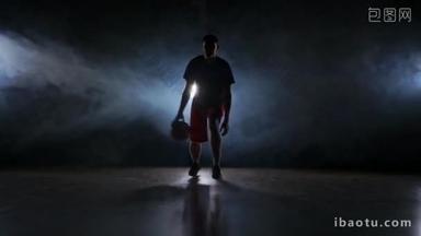 <strong>一个</strong>年轻的成年男子, 篮球运动员运球, 黑暗的室内篮球场